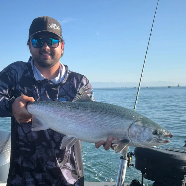 Man holding a large fish on a boat with a clear blue sky and water background